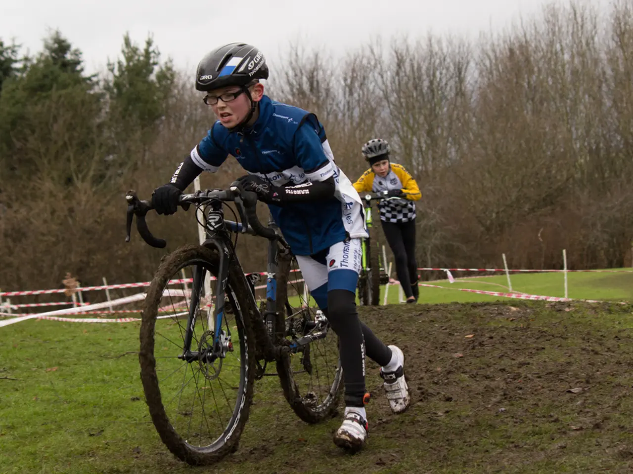 In this image we can see two boys are holding bicycles, they are walking on the ground, and they...