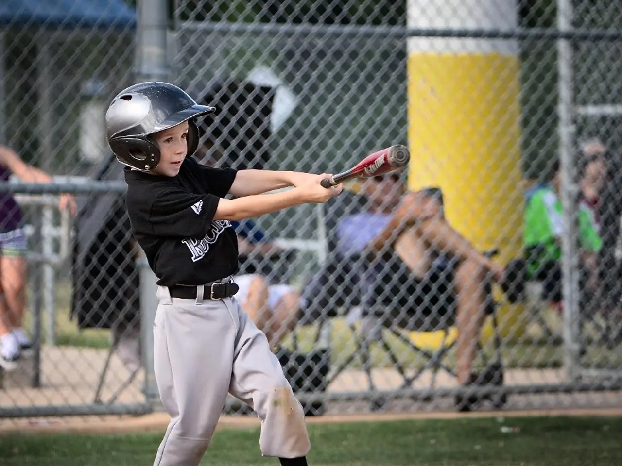 In this image in the foreground there is one boy who is holding a bat and wearing a helmet, at the...