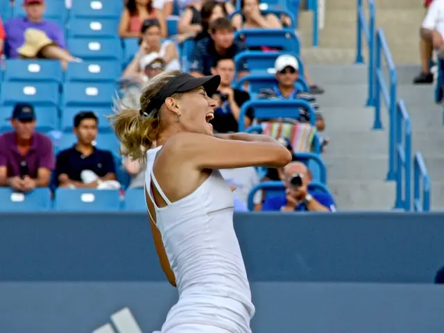 In this picture there is a woman player wearing white top and black cap. Behind there is a blue...